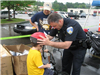 Officer Stands With Small Child While Putting on Helmet