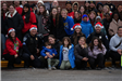 A group of people pose together outside for a picture, they are in front of a red brick building