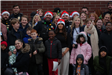 A group of people pose together outside for a picture, they are in front of a red brick building