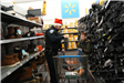 2 People are standing on opposite ends of a shopping cart in a store's shoe aisle