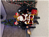 An officer Stands on either side of a sitting santa claus, between 2 Christmas trees