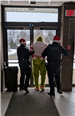 An officer stands on either side of a handcuffed Grinch, walking him to the door
