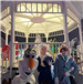 Olaf, Elsa and Anna pose for a photo together in front of the White Gazebo with an illuminated Christmas tree in the background