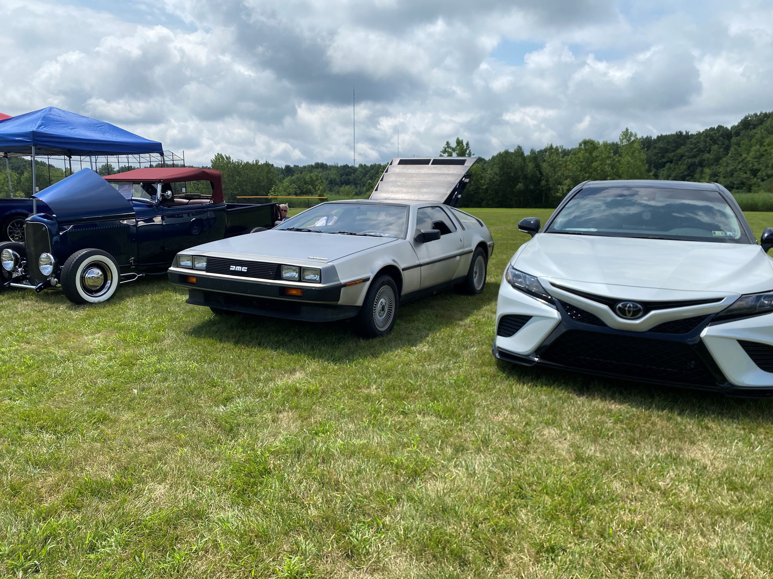 3 Cars, the Car on the Left is a vintage navy car, the middle a DeLorean and the last a Camry