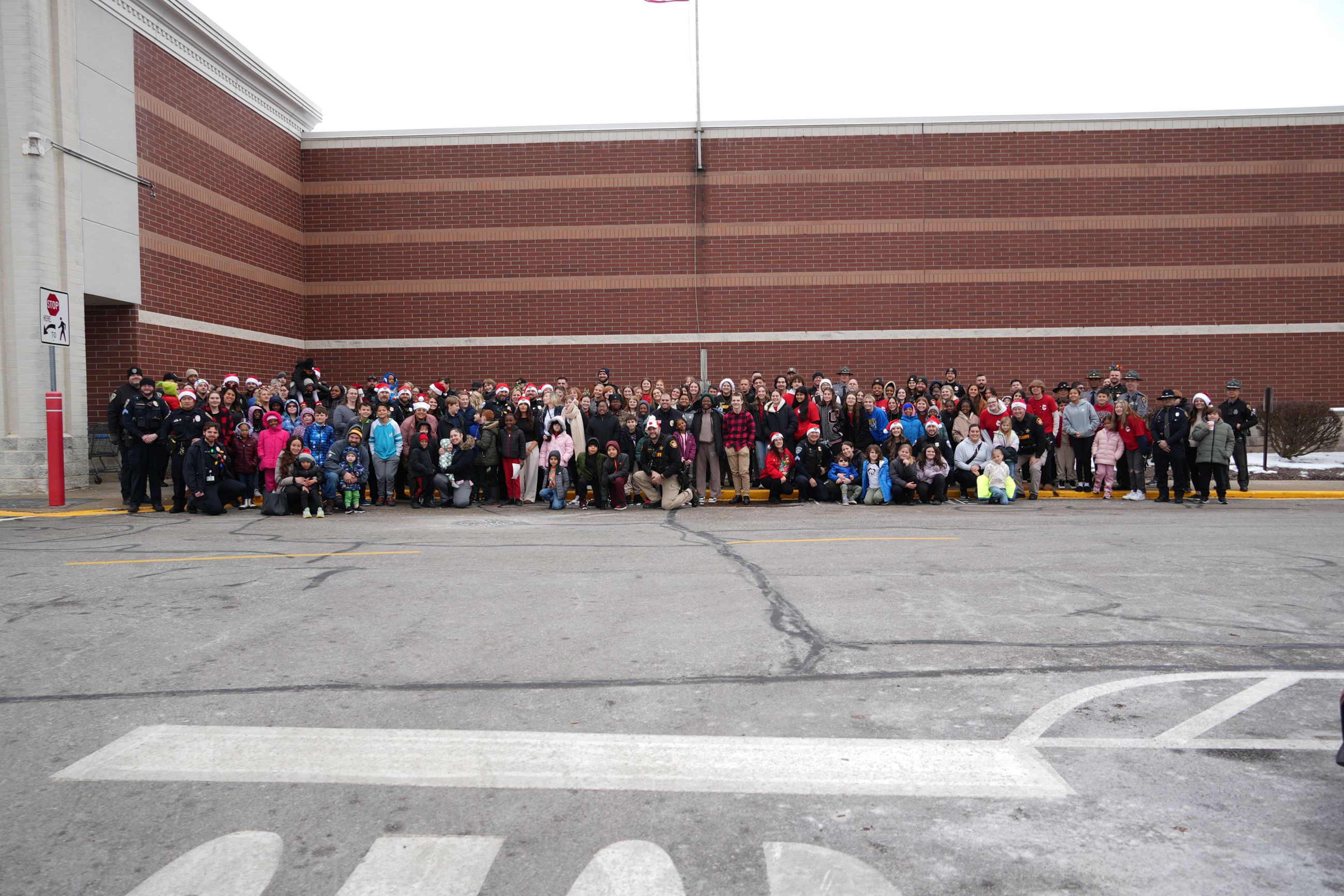 A group of people pose together outside for a picture, they are in front of a red brick building