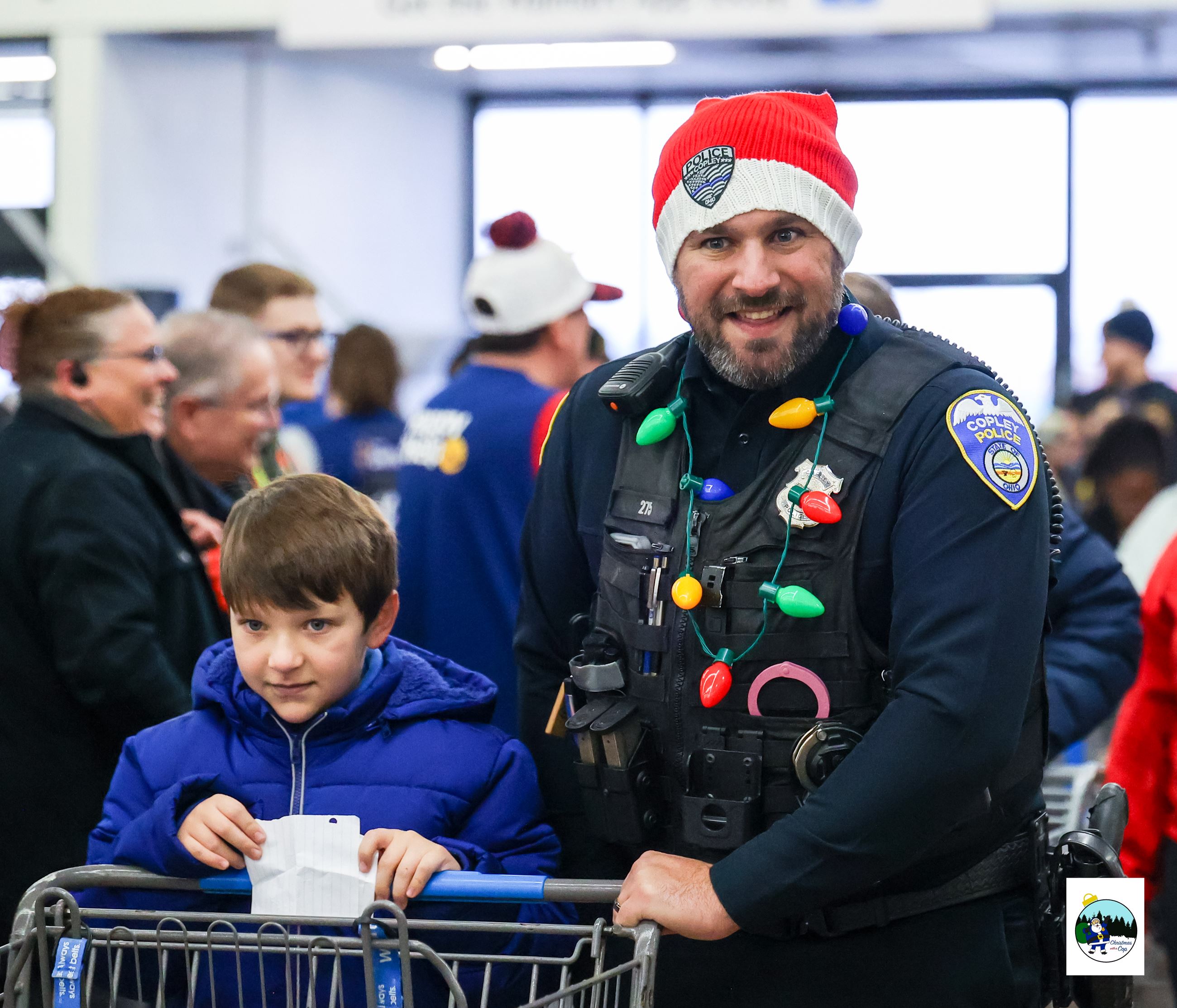An officer and a child are pushing a shopping cart together