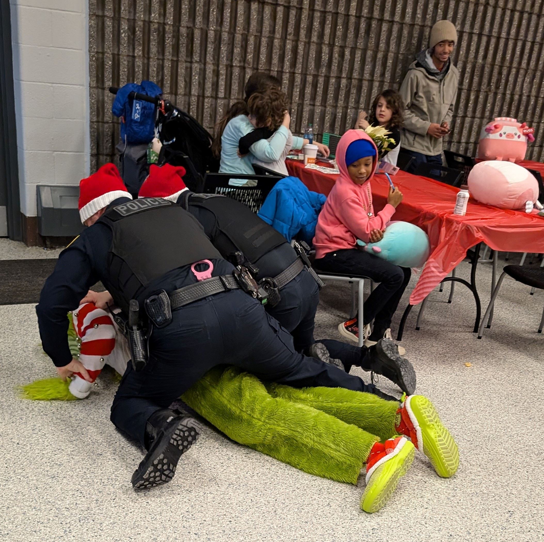 2 Officers are on top of a laying Grinch while they place him into handcuffs