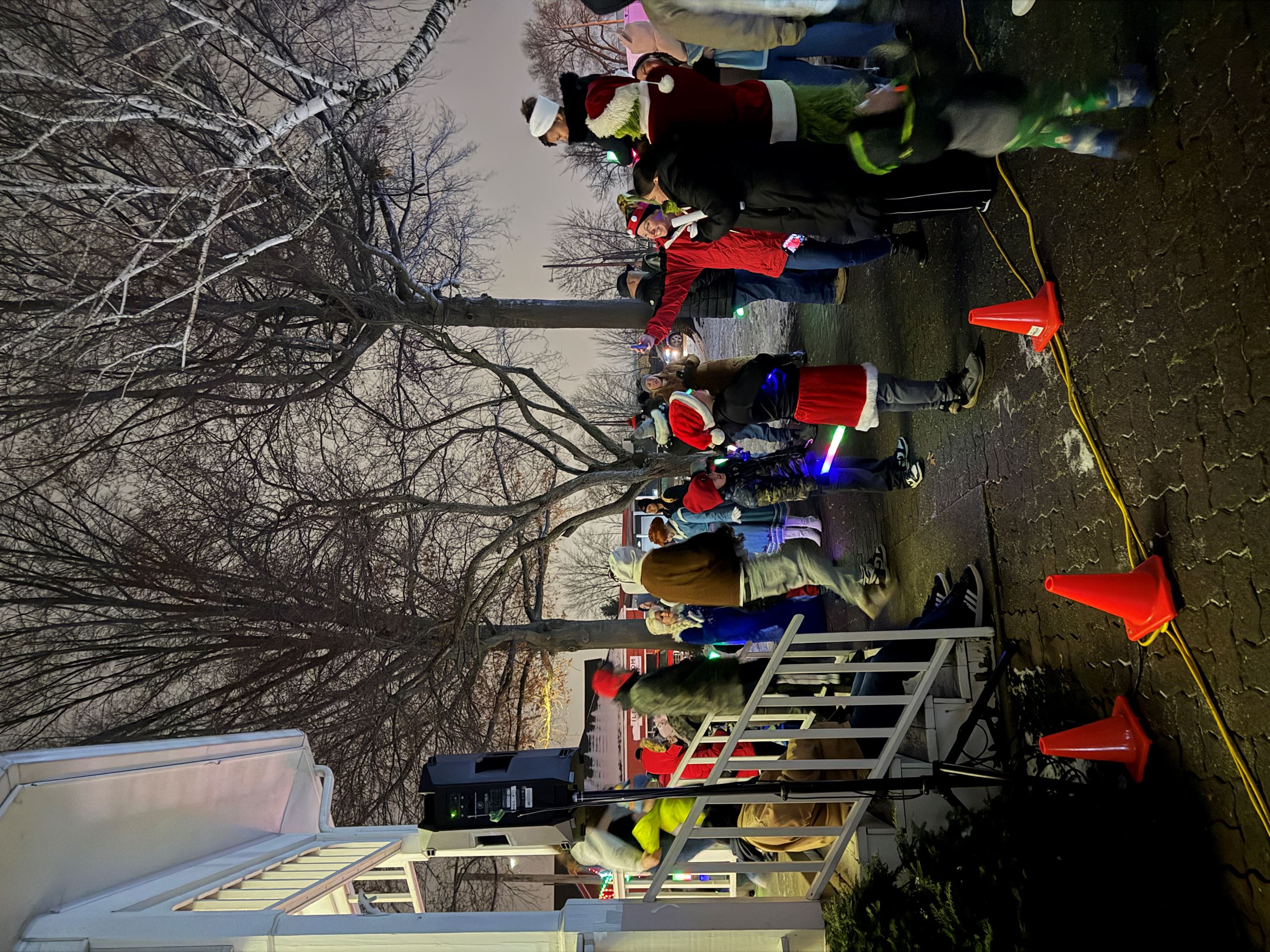 A group of people are seen taking a selfie with the Grinch, the Grinch is holding a child