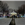 A white gazebo surrounded by snow on the ground, residents and illuminated holiday decorations